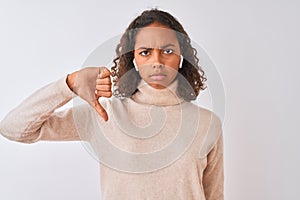 Brazilian woman listening to music using wireless earphones over isolated white background with angry face, negative sign showing