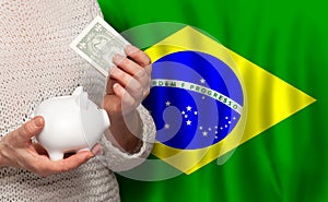 Brazilian woman with money bank on the background of Brazil flag. Dotations, pension fund, poverty, wealth, retirement concept