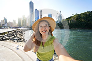 Brazilian woman takes selfie picture in Balneario Camboriu on sunset, Brazil