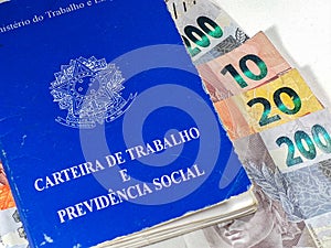 Brazilian Work Card (Carteira de Trabalho) with Brazilian money on white background. Brazilian economy concept.