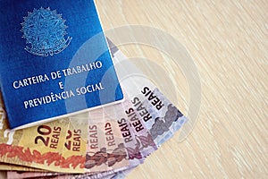 Brazilian work card and social security blue book and reais money bills