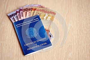 Brazilian work card and social security blue book and reais money bills