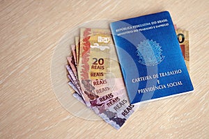 Brazilian work card and social security blue book and reais money bills