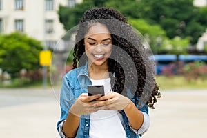 Brazilian young adult woman with retainer sending message with mobile phone