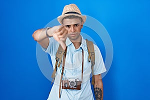 Brazilian young man holding vintage camera looking unhappy and angry showing rejection and negative with thumbs down gesture