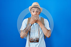 Brazilian young man holding vintage camera shocked covering mouth with hands for mistake