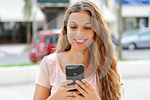 Brazilian young woman walking in the city sending text message on smartphone