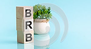 BRB - Big Red Button. Wooden blocks with the word BRB, blu bacground. High level of business profitability