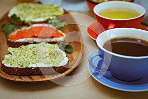 Breackfast toast with salmon and avocado and a cup of tea.