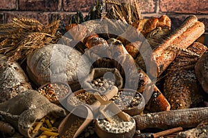 Bread background. Brown and white whole grain loaves wrapped in kraft paper composition on rustic dark wood with wheat ears scatte