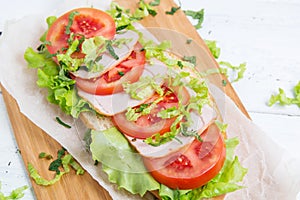 Bread baguette sandwich with ham, tomatoes and lettuce