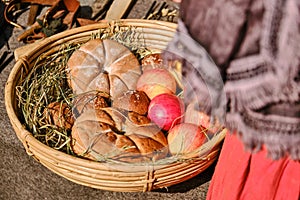 Bread baked on retro technology is with apples in the basket. Reconstruction of cooking in the ancient era. Vintage pastries, cake