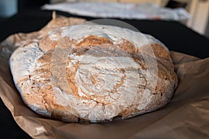 Bread baked in a wood oven. Close up of the piece of bread over the classic caste envelope on a black background