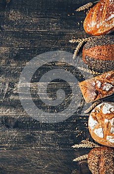 Bread border on wood background with copy space. Whole grain loaves with spikelets. Different types of bread. Bakery