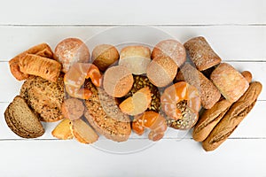 Bread, buns, croissants and other baked goods on wooden table