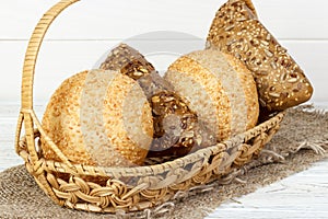 Bread buns in wooden basket on white wooden background
