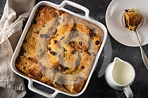 Bread and butter pudding with raisins in white baking dish