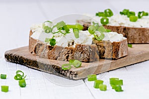 Bread with butter and spread. Concept of healthy breakfast. Spring onion, Vegetables. Wooden white table with copy space