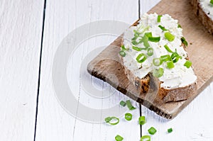 Bread with butter and spread. Concept of healthy breakfast. Spring onion, Vegetables. Wooden white table with copy space