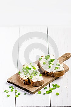 Bread with butter and spread. Concept of healthy breakfast. Spring onion, Vegetables. Wooden white table with copy space