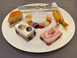Bread, cakes and fruit are arranged on plates for meeting snacks.