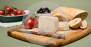 Bread and cheese/Delicious organic cream milk cheese, olives and home-made bread and ripe tomatoes on wooden board.