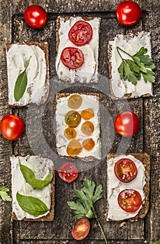 Bread with cheese tomatoes with herbs on a cutting board on wooden rustic background top view