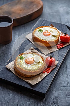 Bread with cheese and yolk for breakfast on black cutting board