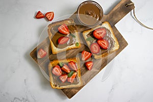 Bread with chocolate paste, dessert morning strawberries on a light background