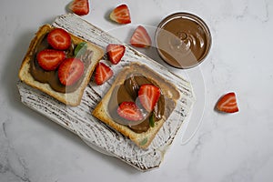 Bread with chocolate paste, cream food strawberries on a light background