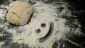 Bread dough with a smiley face in flour.
