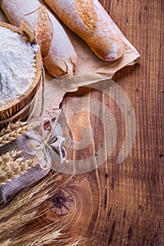 Bread flour in bucket and wheat ears on old wooden