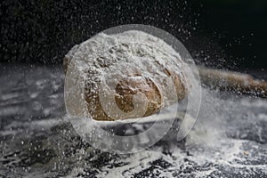 Bread flying with flour splash on floury black table.Creative concept of bakery, baking and cooking .Copy Space