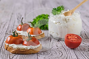 Bread with fresh cottage cheese and cherry tomatoes on a wooden table.