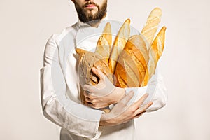 Bread in hand. Freshly baked bread in the hands of. Man with beard holding a lot of bread in hands isolated on white background.