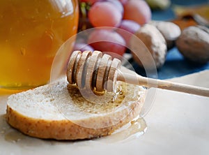 Bread with honey on paper, ripe grapes, nuts and apples on a dark background