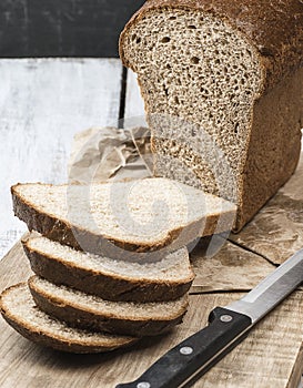 Bread. loaf of freshly baked bread with knife on cutting board. Artisan bread with seeds on table.Rustic sourdough bread