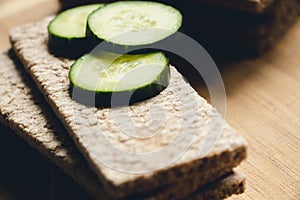 Bread made from rye and wheat flour with freshly sliced and green pieces of cucumber, lie on a board for cutting food. Prepared fo