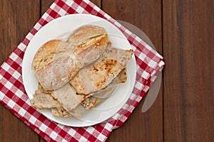 Bread with meat on white plate on brown photo