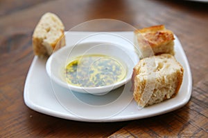 Bread with Olive Oil and Herbs on a white plate at a resturant. Appitizer of Fresh Bread with Olive Oil before the meal is served