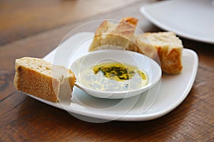 Bread with Olive Oil and Herbs on a white plate at a resturant. Appitizer of Fresh Bread with Olive Oil before the meal is served