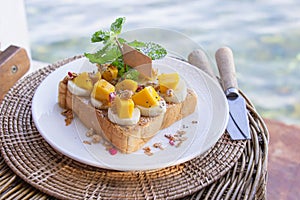 Bread peanut butter in white plate put banana and mango decorated with mint leaves