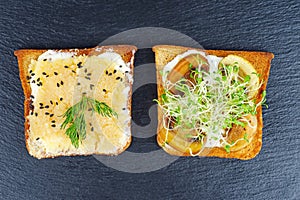 Bread pieces with delicious cod caviar, grilled mushrooms and sprouted alfalfa on black stone slate background