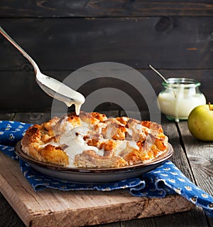 Bread pudding. Traditional English breakfast casserole with apples and vanilla sauce. Bread and butter pudding on old wooden