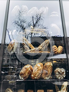 Bread in a restaurant window. Reflection of trees in a glass window.