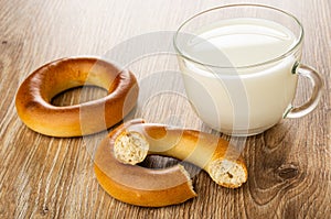 Bread rings baranka, broken baranka, cup with milk on table photo