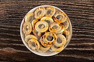 Bread rings with poppy in bowl on wooden table. Top view