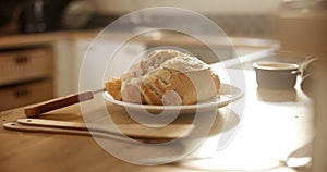 Bread, roll and plate in kitchen for breakfast, meal or morning snack on wooden table. Closeup of interior, wheat or cut