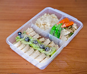 Bread salad roll wrap sandwich with berry, lettuce, .kiwi ,bananas and bean ,.chicken breast with rice on the rice box