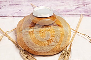 Bread with salt is a traditional symbol of hospitality. Round wheat bread with salt shaker on top.